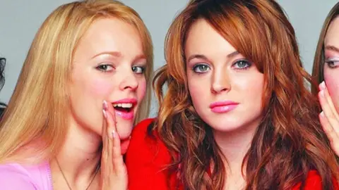 Rachel McAdams whispers in Lindsay Lohan's ear in the poster for Mean Girls (2004).